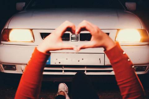 Myriam Correia em close-up com mãos em coração enquadrando os faróis do Seat Ibiza durante retrato noturno na Quinta da Cardiga, Golegã. Uma declaração de amor ao carro. Duo Capuano Fotografia.'