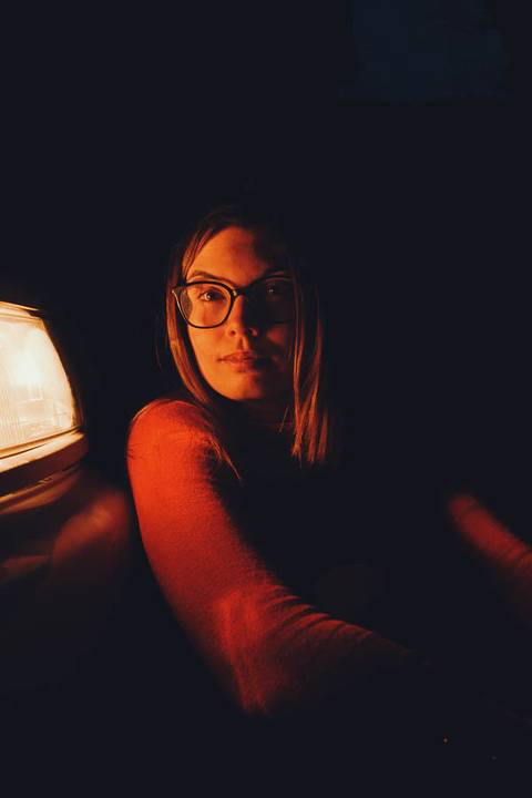 Myriam Correia dentro do Seat Ibiza em retrato noturno íntimo, iluminada pela luz quente dos faróis na Quinta da Cardiga, Golegã. A paixão pelo carro captada de dentro para fora. Duo Capuano.'