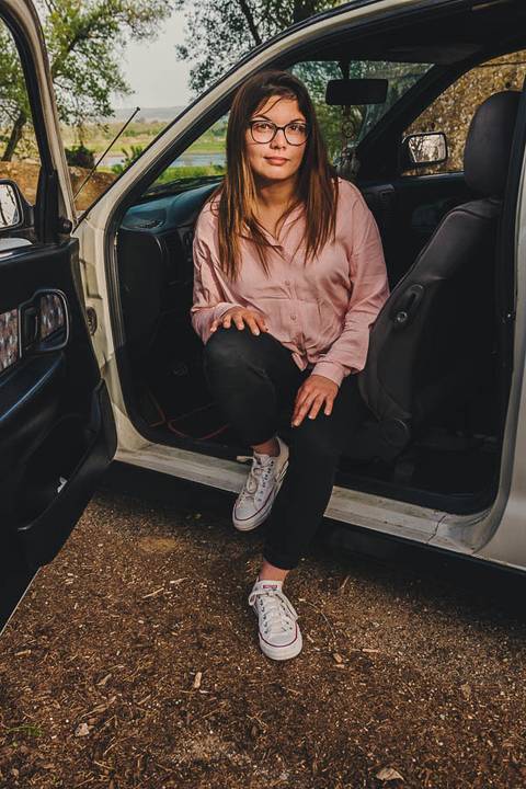 Myriam Correia sentada descontraidamente na porta aberta do seu Seat Ibiza durante sessão de retrato feminino na Quinta da Cardiga, Golegã. Um momento natural e autêntico. Duo Capuano Fotografia.'