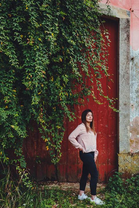 Myriam Correia de look branco junto a parede vermelha com hera durante sessão de retrato feminino na Quinta da Cardiga, Golegã. Um contraste de cores que cria um resultado marcante. Duo Capuano.'