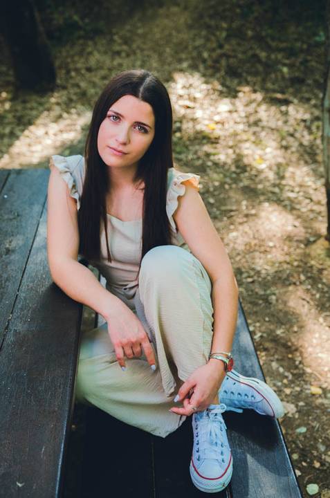 Mulher sentada de lado em rochas do parque com postura descontraída – retrato feminino ao ar livre no Parque do Bonito, Santarém, primavera'