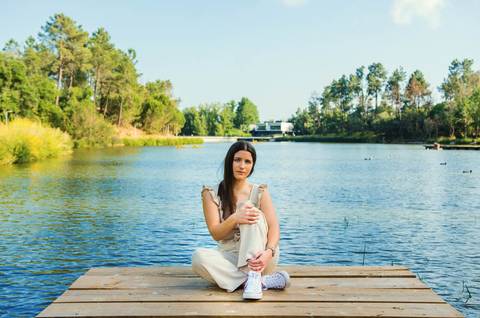 Retrato feminino sentada no pontão de madeira com lago tranquilo ao fundo – fotografia de retrato no Parque do Bonito, Santarém'
