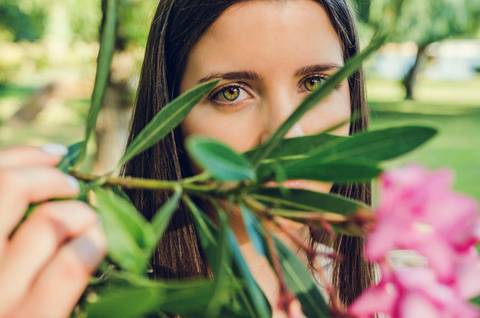 Close-up artístico de olhos verdes femininos entre folhas e flores cor-de-rosa – fotografia de retrato no Parque Verde do Bonito, Santarém'