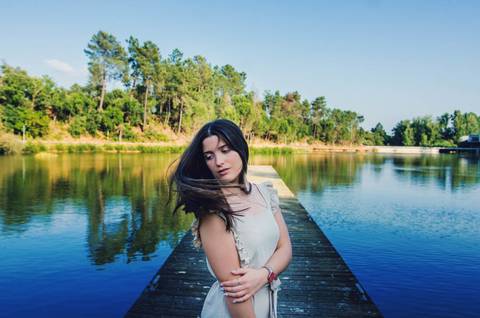 Retrato feminino no pontão do lago com cabelo ao vento e sorriso natural – fotografia de retrato no Parque Verde do Bonito, Santarém'