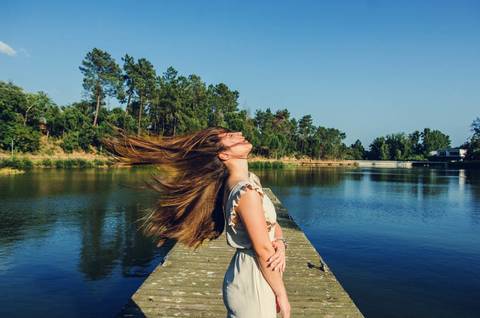 Mulher no pontão do lago com cabelo ao vento e postura dinâmica – retrato feminino ao ar livre no Parque Verde do Bonito, Santarém'
