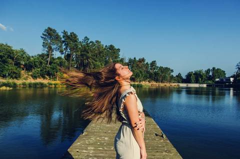 Retrato feminino de pé no pontão com pose lateral e lago ao fundo – fotografia de retrato no Parque Verde do Bonito, Santarém, primavera'