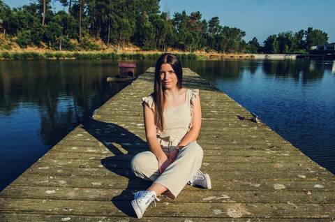 Retrato feminino sentada no pontão de madeira com lago azul e floresta ao fundo – sessão de retrato no Parque Verde do Bonito, Santarém'
