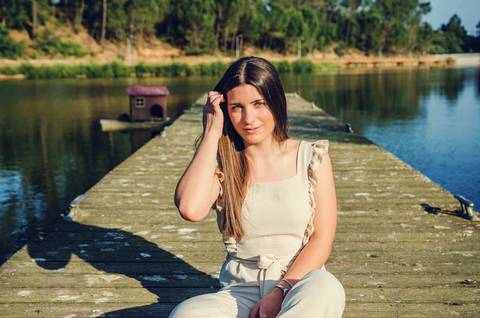 Retrato feminino sentada no pontão com mão no rosto e olhar pensativo – fotografia de retrato no Parque Verde do Bonito, Santarém'