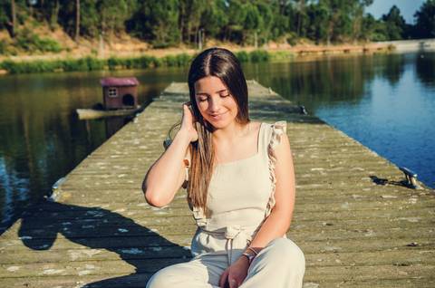 Retrato feminino sentada no pontão de jeans com lago ao fundo – fotografia de retrato casual ao ar livre no Parque do Bonito, Santarém'