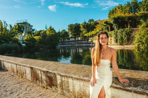 Fotografia feminina de corpo inteiro junto ao lago em Torres Novas. Susana em vestido branco com fundo de reflexo de água e salgueiros. Sessão fotográfica individual ao ar livre por Duo Capuano.'
