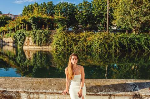 Susana apoiada em corrimão de pedra junto ao lago com reflexo de árvores. Sessão fotográfica feminina individual ao pôr do sol em Torres Novas por Duo Capuano Fotografia.'