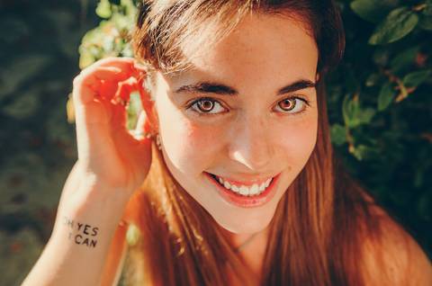 Close-up de retrato feminino com sorriso radiante. Sessão fotográfica individual da Susana ao ar livre no Jardim das Rosas, Torres Novas. Fotografia feminina descontraída por Duo Capuano.'