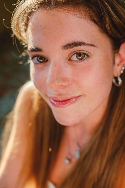 Retrato feminino em close com luz quente de fim de tarde. Sorriso natural e olhar expressivo da Susana. Sessão fotográfica individual no Jardim das Rosas, Torres Novas, por Duo Capuano.'