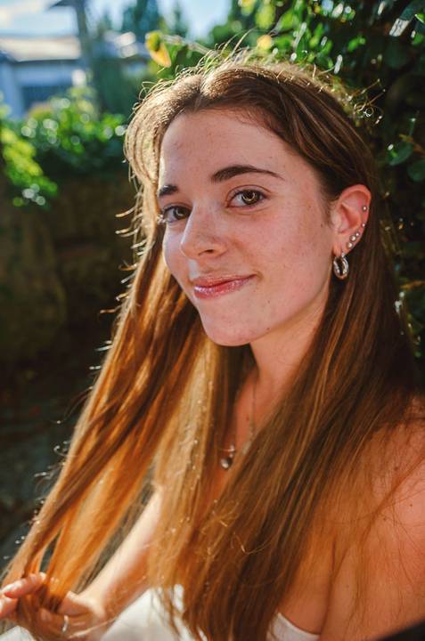 Retrato em close da Susana com cabelo comprido e expressão serena. Fotografia feminina descontraída ao ar livre no Jardim das Rosas, Torres Novas. Sessão individual por Duo Capuano.'