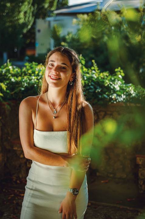 Fotografia feminina ao ar livre com sorriso genuíno e acessórios delicados. Susana em top branco rodeada por folhas verdes. Sessão individual no Jardim das Rosas, Torres Novas, Duo Capuano.'