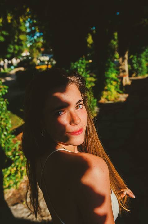 Close-up criativo de rosto feminino com luz intensa e sombras expressivas. Retrato artístico de Susana com batom vermelho. Sessão individual no Jardim das Rosas, Torres Novas, Duo Capuano.'