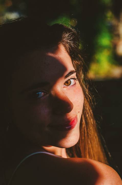 Retrato feminino em close-up com jogo de cores e desfoque criativo ao fundo. Susana com expressão intensa e batom vermelho. Sessão individual por Duo Capuano no Jardim das Rosas, Torres Novas.'