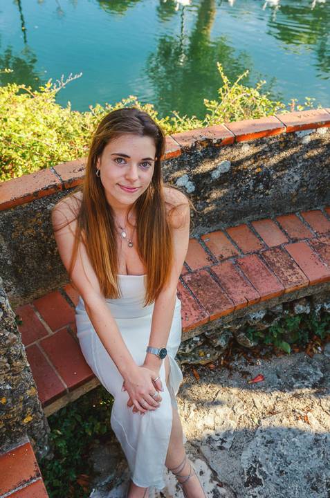 Retrato feminino de close-up com cabelo ruivo comprido e sorriso caloroso. Susana posa em muro de pedra rústico. Sessão fotográfica individual ao ar livre em Torres Novas, por Duo Capuano.'