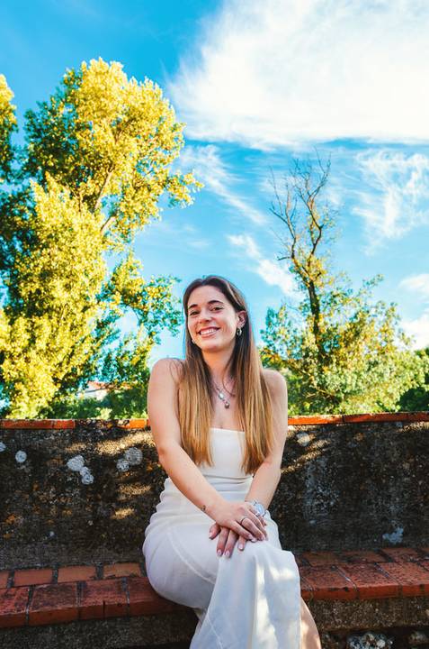 Susana com expressão alegre e natural ao lado de lago com reflexo de árvores. Vestido branco numa pose elegante ao ar livre. Sessão fotográfica feminina individual em Torres Novas por Duo Capuano.'