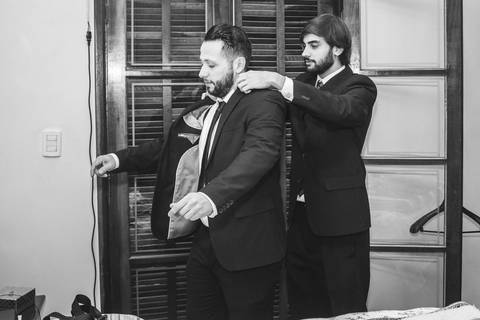 Noivo Rafael e padrinho em preto e branco na porta antes da cerimônia de casamento em São Paulo, momento entre amigos'