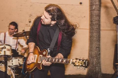 Músico tocando guitarra solo durante banda ao vivo em casamento Camila e Rafael em São Paulo com iluminação ambiente'