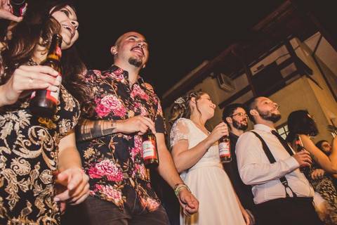 Convidados dançando com roupas coloridas durante festa de casamento Camila e Rafael em São Paulo com iluminação ambiente'