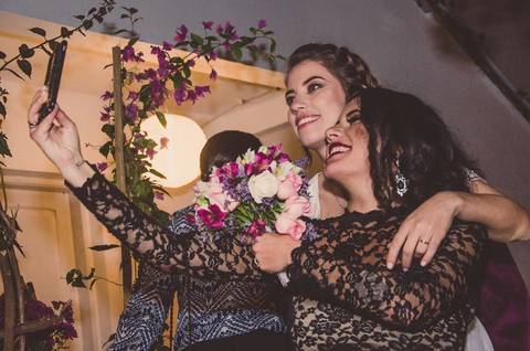 Casal Camila e Rafael cortando bolo de casamento durante festa em São Paulo, momento especial com flores amarelas ao redor'