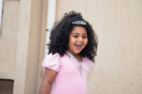 criança sorrindo, feliz ao ver a decoração da festa infantil em sao paulo no tema das princesas, vestido de princesa'