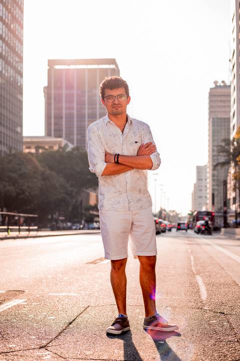 ensaio masculino portrait do fotografo em sao paulo na avenida paulista no meio da rua com seu look branco e  seus oculos no por do sol golden hour'