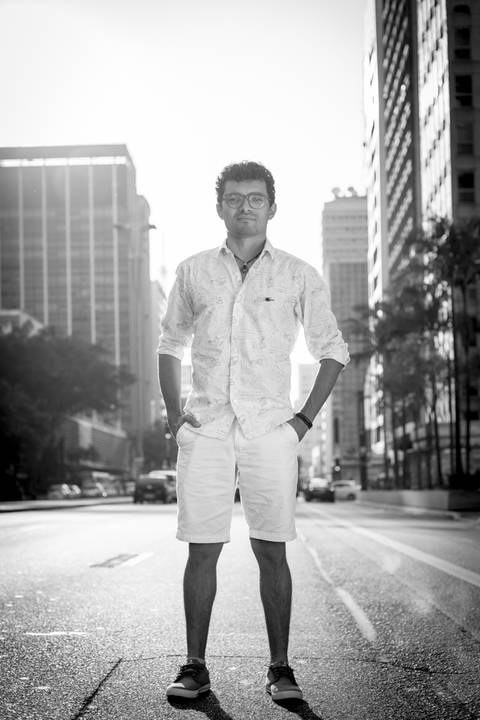 ensaio masculino portrait do fotografo em sao paulo na avenida paulista no meio da rua com seu look branco e  seus oculos em preto e brancono por do sol golden hour'