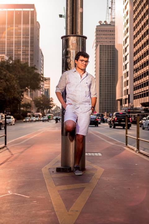 moda, luxo, ensaio masculino portrait do fotografo em sao paulo na avenida paulista no meio da rua com seu look branco e  seus oculos no por do sol golden hour'