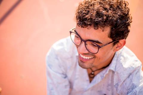 moda, luxo, ensaio masculino portrait do fotografo em sao paulo na avenida paulista sentado no meio da rua com seu look branco e  seus oculos no por do sol golden hour, cachos'