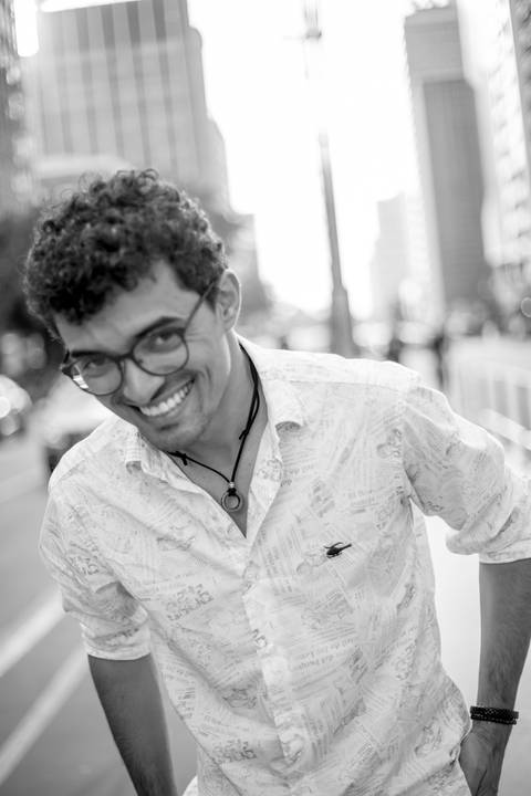 moda, luxo, ensaio masculino portrait do fotografo em sao paulo na avenida paulista sentado no meio da rua com seu look branco e  seus oculos no por do sol golden hour, cachos'