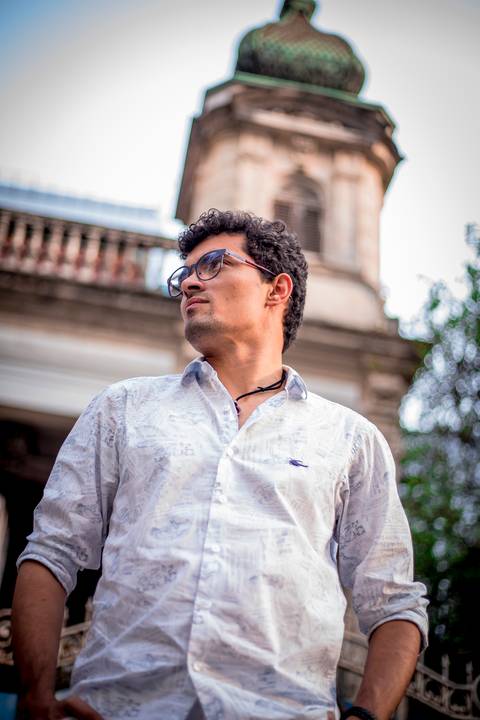 moda, luxo, ensaio masculino portrait do fotografo em sao paulo na avenida paulista sentado no meio da rua com seu look branco e  seus oculos no por do sol golden hour, cachos'