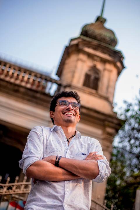 moda, luxo, ensaio masculino portrait do fotografo em sao paulo na avenida paulista sentado no meio da rua com seu look branco e  seus oculos no por do sol golden hour, cachos'