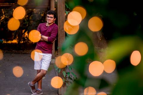 moda, luxo, ensaio masculino portrait do fotografo em sao paulo na avenida paulista sentado no meio da rua com seu look branco e  seus oculos no por do sol golden hour, cachos, luzes de fada'