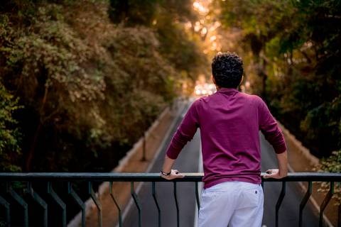 moda, luxo, ensaio masculino portrait do fotografo em sao paulo na avenida paulista sentado no meio da rua com seu look branco e  seus oculos no por do sol golden hour, cachos'
