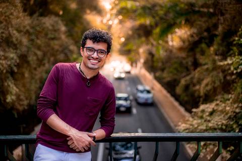 moda, luxo, ensaio masculino portrait do fotografo em sao paulo na avenida paulista sentado no meio da rua com seu look branco e  seus oculos no por do sol golden hour, cachos'