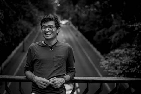 moda, luxo, ensaio masculino portrait do fotografo em sao paulo na avenida paulista sentado no meio da rua com seu look branco e  seus oculos no por do sol golden hour, cachos, preto ebranco'