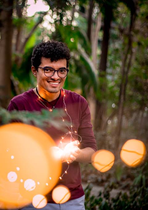 moda, luxo, ensaio masculino portrait do fotografo em sao paulo na avenida paulista sentado no meio da rua com seu look branco e  seus oculos no por do sol golden hour, cachos, luzes de fada'