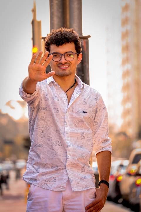 moda, luxo, ensaio masculino portrait do fotografo em sao paulo na avenida paulista sentado no meio da rua com seu look branco e  seus oculos no por do sol golden hour, cachos'