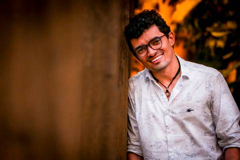 moda, luxo, ensaio masculino portrait do fotografo em sao paulo na avenida paulista sentado no meio da rua com seu look branco e  seus oculos no por do sol golden hour, cachos, luzes de fada'