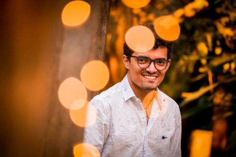 moda, luxo, ensaio masculino portrait do fotografo em sao paulo na avenida paulista sentado no meio da rua com seu look branco e  seus oculos no por do sol golden hour, cachos, luzes de fada'