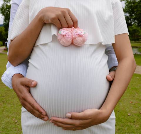 Barriga de gestante com sapatinho de bebê'