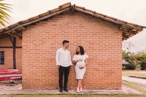Casal em ensaio de gestante posando em casa de tijolinhos'