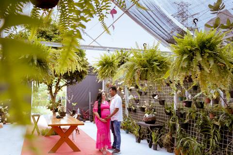 Casal posando em um orquidário durante um ensaio de gestante'