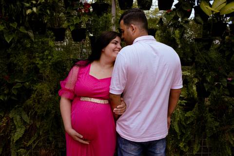 casal em um orquidário durante um ensaio de gestante, ela de frente e ele de costas'