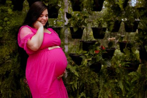 gestante posando com a mão na barriga durante um ensaio de gestante '