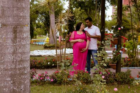 casal posando em um jardim durante um ensaio de gestante'