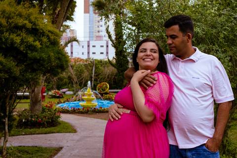 casal posando próximo a uma fonte durante um ensaio de gestante'